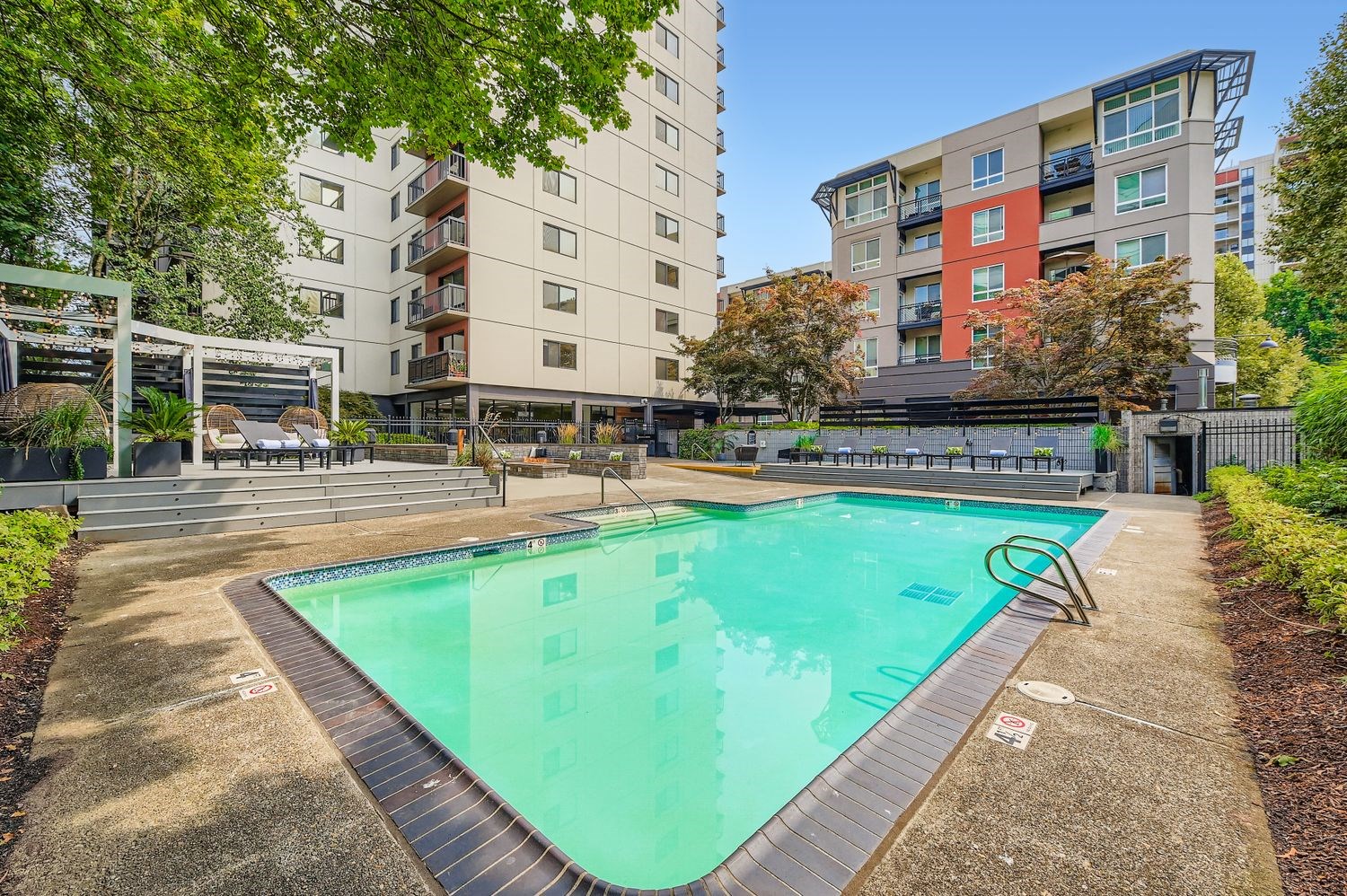 Modern Studio Apartments in Downtown Portland, OR - Linc 245 - Swimming Pool with Lounge Chairs, Daybeds, Landscaping, and View of the Apartments.